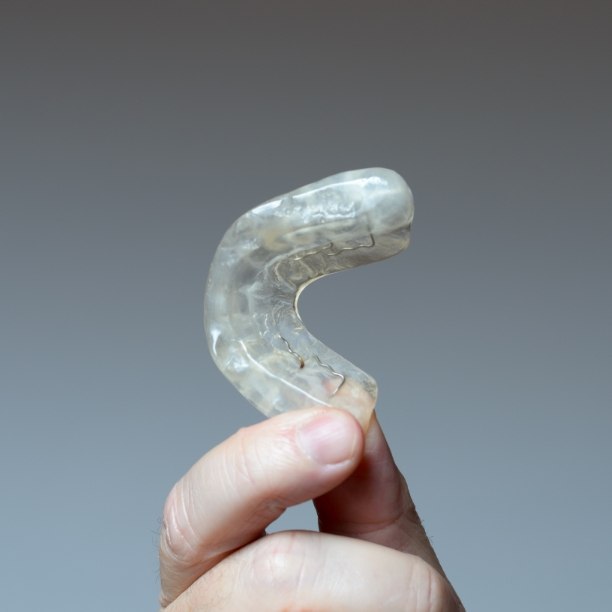 Hand holding a clear nightguard for bruxism