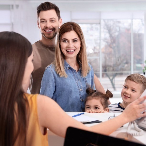 Family checking in at dental office reception desk