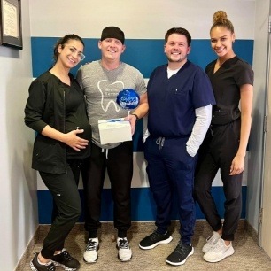 Dental team members holding gift for dental patient