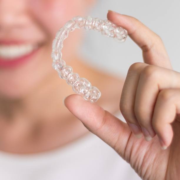 Hand holding an Invisalign clear aligner