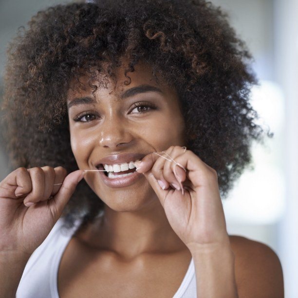 Woman flossing to prevent dental emergencies