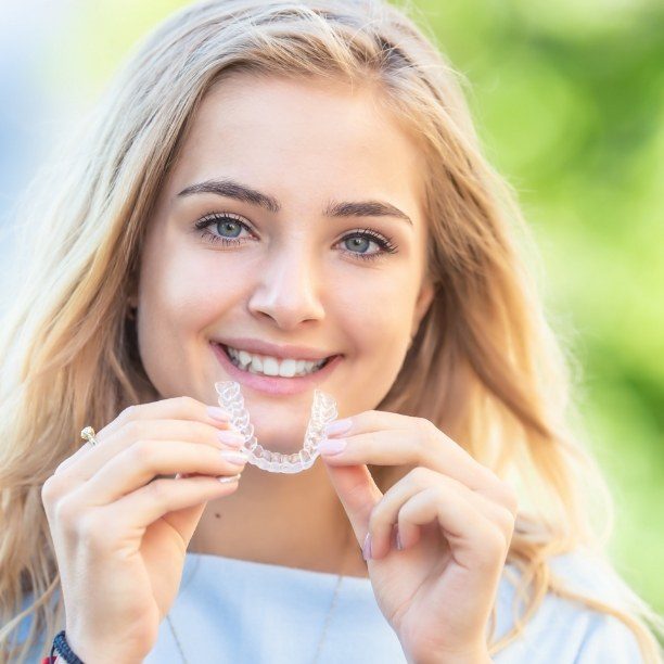 Smiling dental patient placing an Invisalign clear braces tray