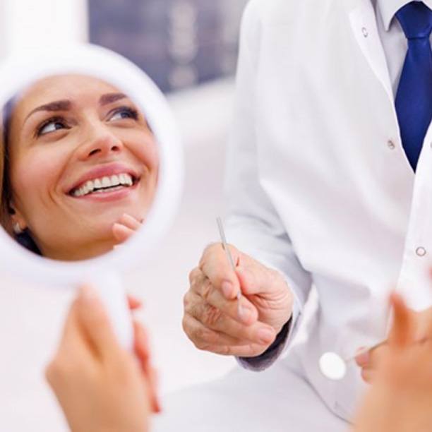 Reflection of dental patient’s smile in hand mirror
