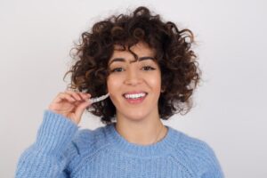 Young woman with curly hair holding ClearCorrect clear aligner