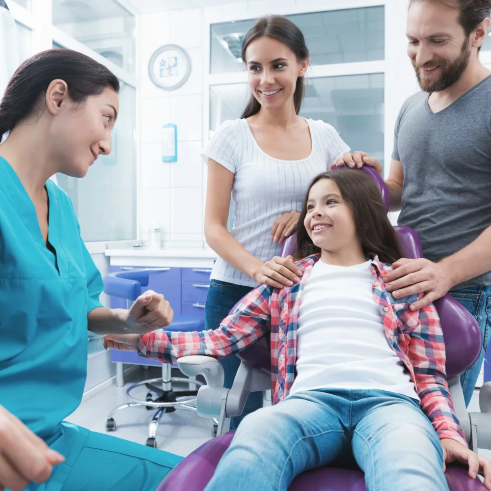 Girl smiling in the dental chair with her parents during a pediatric dentistry visit in Plano, TX