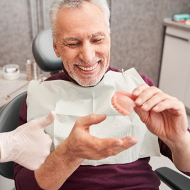 Older man smiling with his new dentures