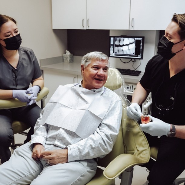 Plano dentist and dental team member talking to older man in dental chair